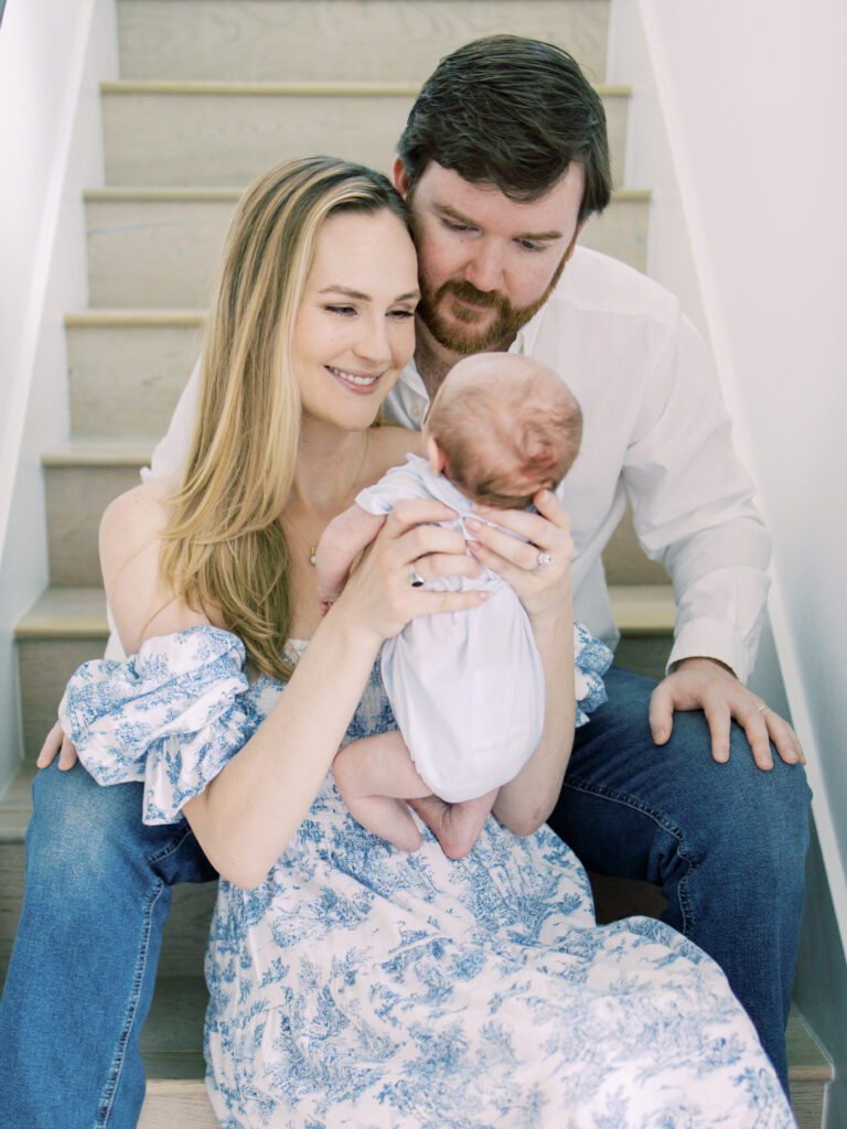 Parents adore their newborn as they smile and coo at him during their newborn session.