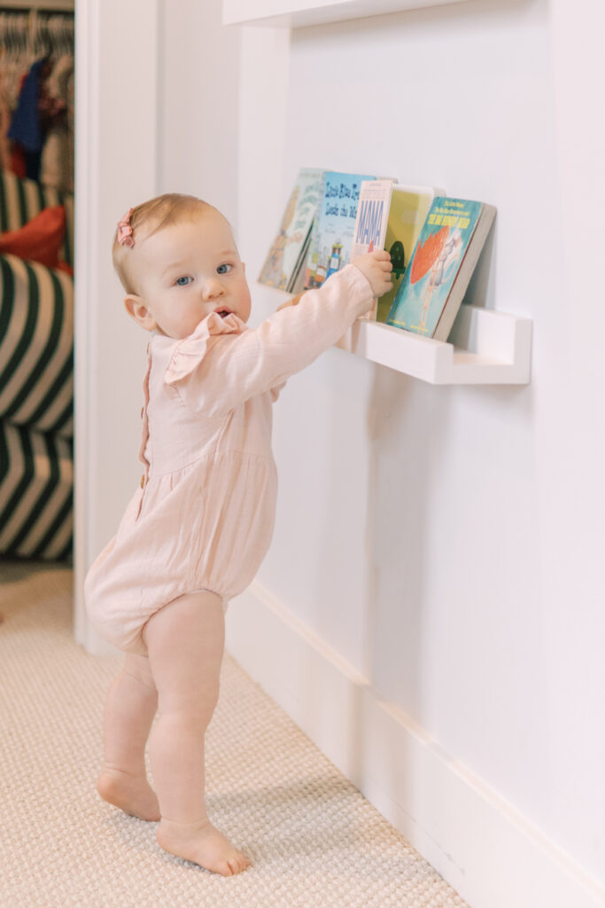 Toddler pulls book off of a floating bookshelf.